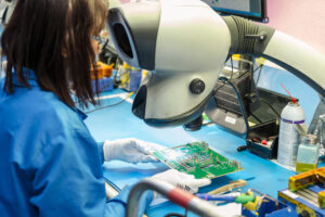 Technician performing precision PCB inspection and electronics assembly in an advanced manufacturing environment